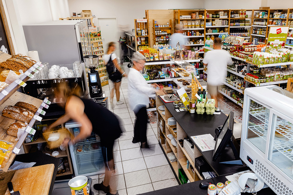 KI generiert: Ein Bio-Lebensmittelladen mit Menschen, die Produkte kaufen und regale auffüllen.