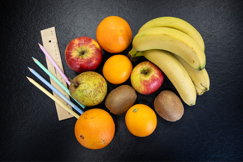 KI generiert: Verschiedene Früchte, Buntstifte und ein Lineal auf schwarzem Hintergrund. Text ist nicht vorhanden.